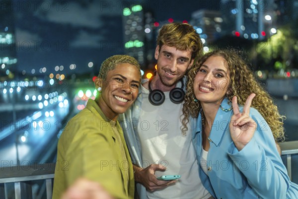 Group of diverse friends smiling and posing for a selfie at night, celebrating friendship and youth