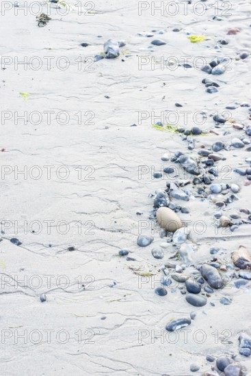 Pattern in sand with scattered stones on a quiet sandy beach, drainage channels, runoff water,