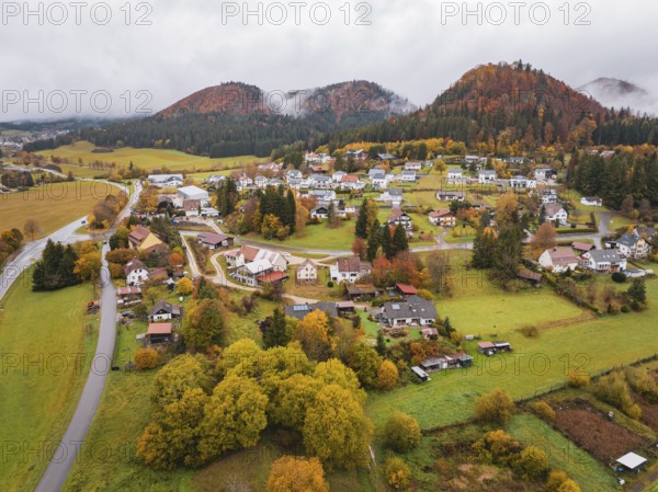 Aerial view of a village surrounded by autumnal hills and clouds of fog, Wehingen, Tuttlingen