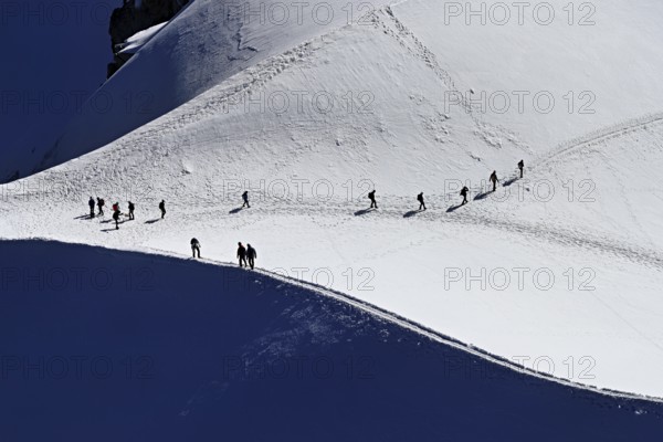 A group of mountaineers runs across a snow-covered mountain, Aiguille du Midi, Chamonix-Mont-Blanc,
