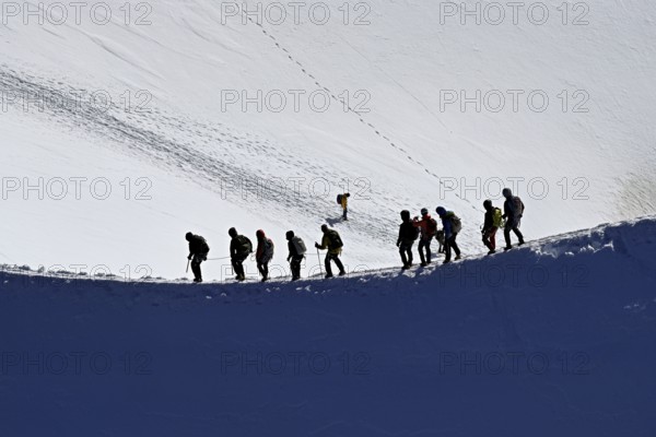 A group of mountaineers runs across a snow-covered mountain ridge, Aiguille du Midi,