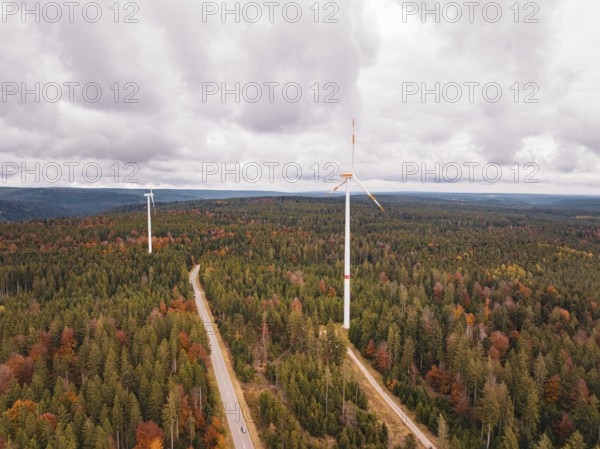 Wind turbines in autumn forest surrounded by clouds and roads, Simmersfeld wind farm, Germany