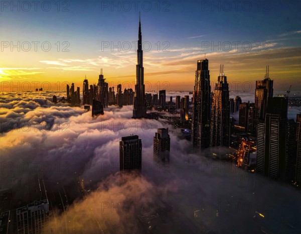 City scape emerging from a dense enveloping fog in sunrise and skyscrapers piercing the haze, big