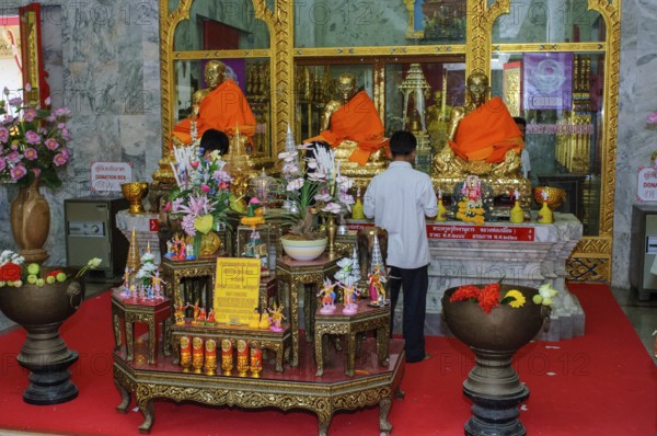 Buddhist believers Buddhists pray making offerings to statues of Buddhist monks covered with gold