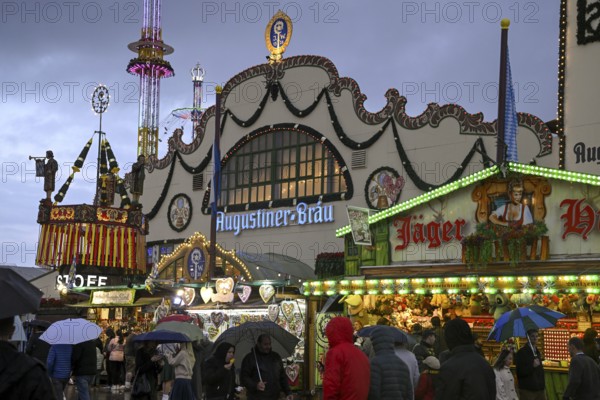 Oktoberfest visitors with umbrellas, rainy meadows, Augustiner festival tent, Munich, Bavaria,