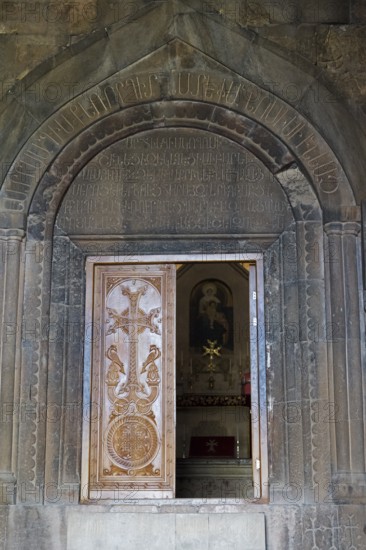 Wooden door with cross in artistically engraved stone archway, Noravank Monastery, Surb Karapet