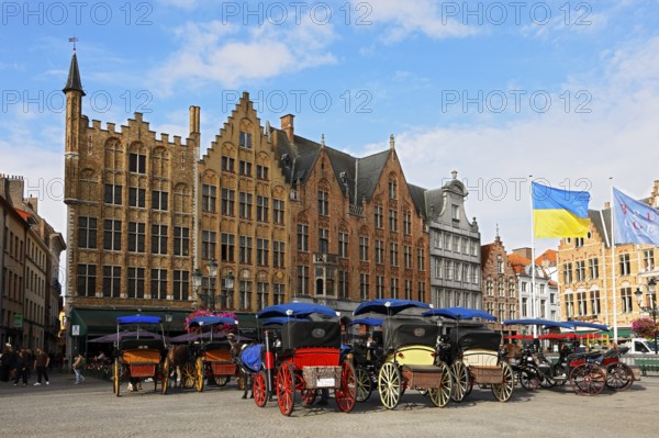 Historic houses on the market square in the old town of Bruges with horse-drawn carriages, Grote