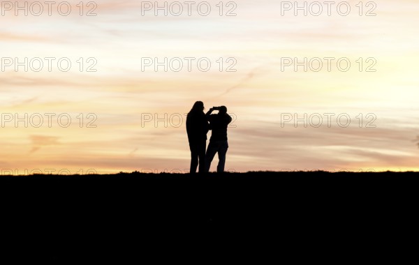 Walkers with mobile phone at sunset on a dike, Fehmarn island, 13.10.2025, Fehmarn,