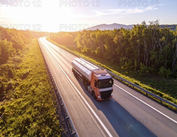 Petrol cargo truck lorry tanker driving on highway hauling oil products at sunrise, wide hilly