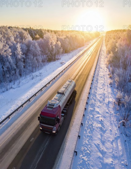 Petrol cargo truck lorry tanker driving on highway hauling oil products at sunrise, wide snowy