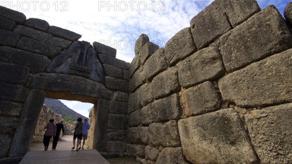 Group of visitors pass through a huge stone gate, lion gate, Mycenae, archaeological site, UNESCO
