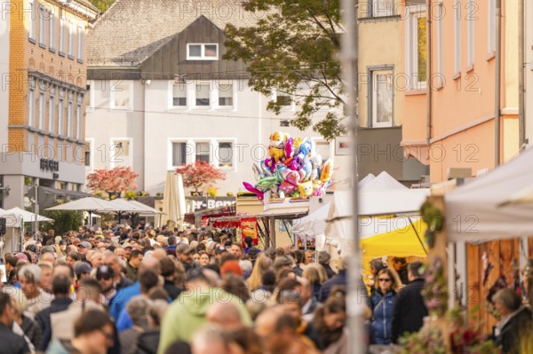Busy shopping street in autumn, people strolling between modern buildings and colorful shops,