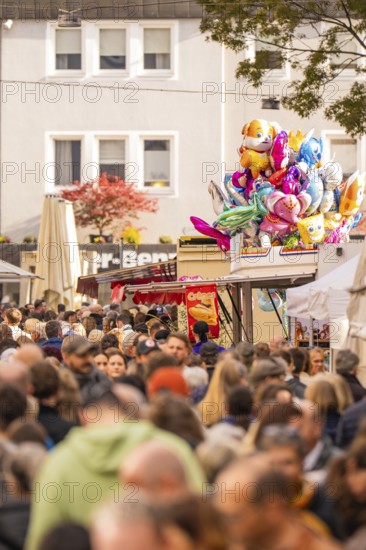 Busy shopping street in autumn, people strolling between modern buildings and colorful shops,