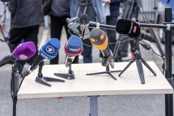 Microphones from various radio stations, television stations, standing on the table, at a press