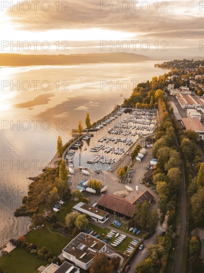 A harbor with anchored boats at sunset, surrounded by an urban landscape in autumn, Überlingen,