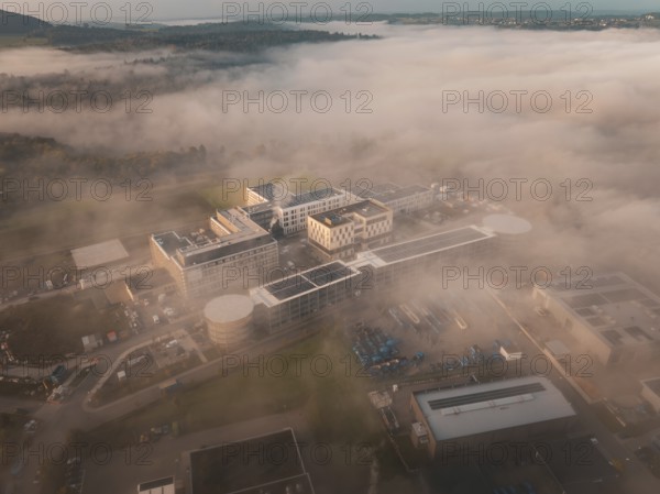 Building in an industrial area seen from above in fog, surrounded by landscape at daybreak, new