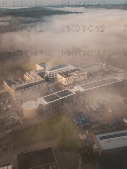 Aerial view of a complex of buildings in thick morning fog, modernly embedded in a natural