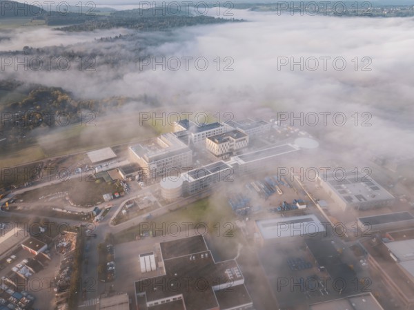 Wide angle view of an industrial center in fog surrounded by natural landscape at dawn, new