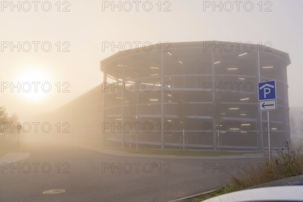 Misty street with parking garage at sunrise, mystical atmosphere, new hospital health campus