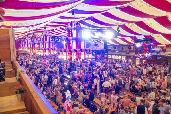 Fully occupied marquee with people in traditional costumes and colourful decorations, Cannstatter