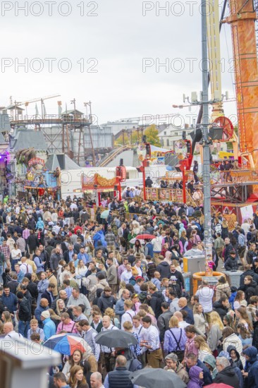 Large crowd at a lively folk festival with various rides and a lively atmosphere, Cannstatter Wasen
