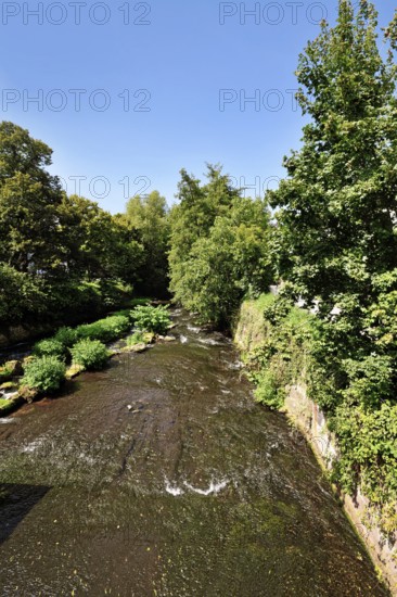 Ettlingen, Germany - August 13th 2025: Alb river flowing through Ettlingen in summer with trees and