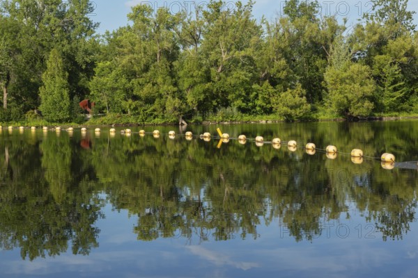 String of yellow cautionary navigation marker buoys on water surafce of river serving to warn,