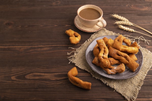 Crunchy biscuit Brushwood cookies sprinkled with powdered sugar on brown wooden background and