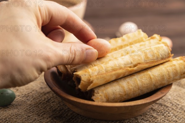 Waffles with caramel with hand on brown wooden background and linen textile, cup of coffee, side