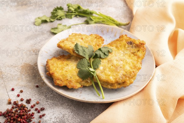 Fried crispy Chicken pancakes on brown concrete background and orange linen textile. side view,