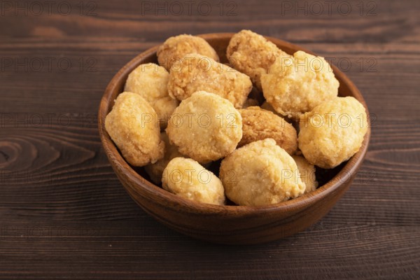 Fried crispy Chicken Nuggets on brown wooden background. side view, close up