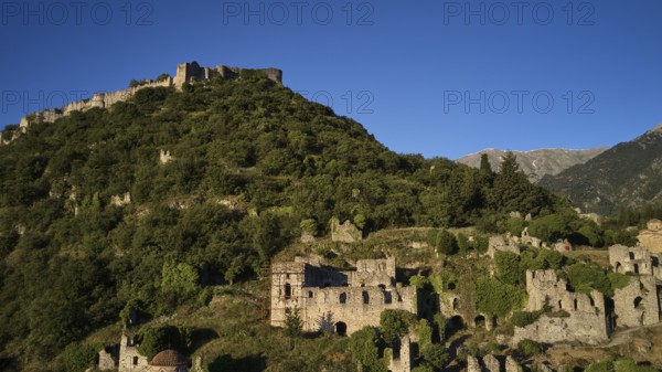 Drone image, Byzantine castle perched on a wooded hill under a blue sky, Mystras, Mistra, UNESCO