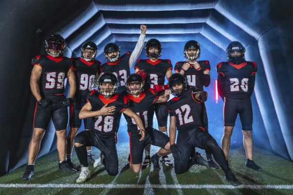 American football team players posing confidently with a victorious gesture, emerging from a