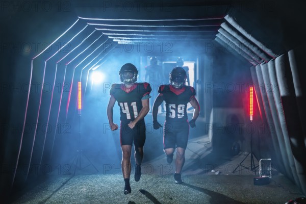 American football players burst from a smoky stadium tunnel in helmets and jerseys, running onto