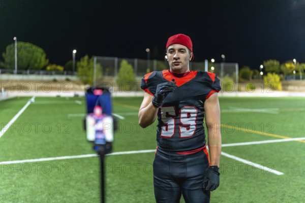 Football player in uniform recording video on a smartphone with a lavalier microphone, creating new
