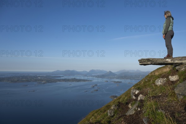 Woman with walking sticks standing on a ledge, Rørsethornet stone stairs, with 3292 steps one of