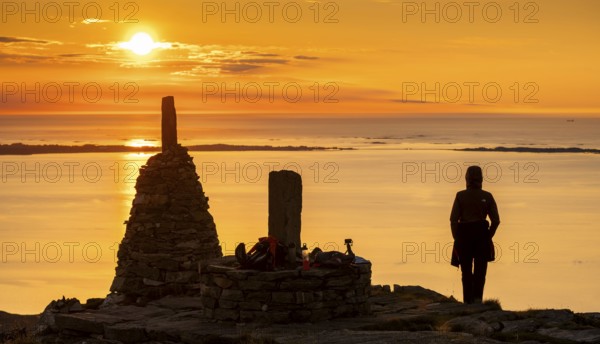 Silhouette of a woman watching the sunset next to cairns, Rørsethornet stone staircase, with 3292