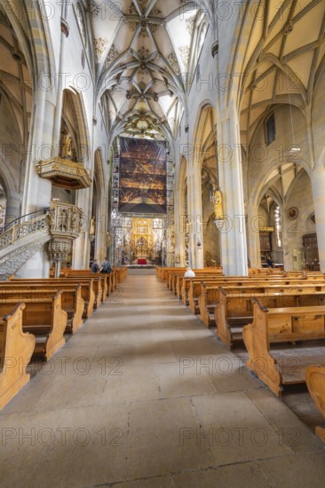 Gothic church with detailed construction, wooden benches and large painted banner above the altar