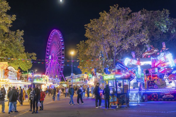 Lively night shot with illuminated Ferris wheel and colourful festival stands, Cannstatter Wasen