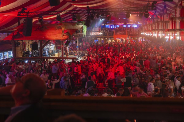 A well-attended marquee with red lights and a cheerful party atmosphere, Cannstatter Wasen folk