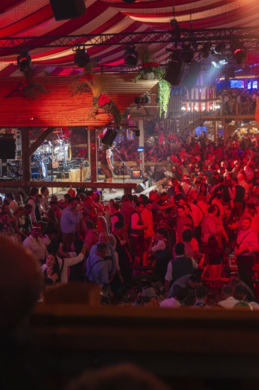 Crowded hustle and bustle in an atmospherically illuminated beer tent at the festival, Cannstatter