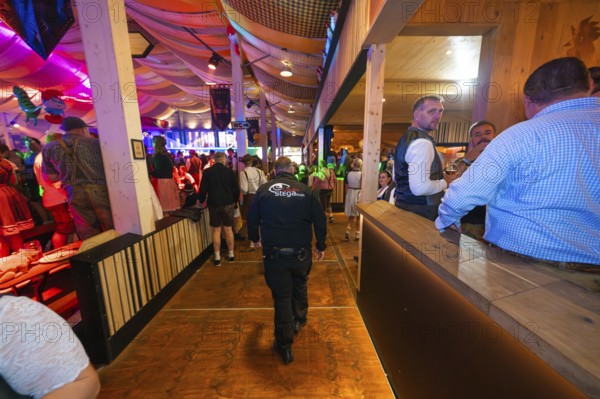 Security guard in a well-filled marquee with atmospheric lighting, Cannstatter Wasen folk festival,