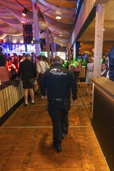 Security guard in a well-attended beer tent with festival decorations, Cannstatter Wasen folk