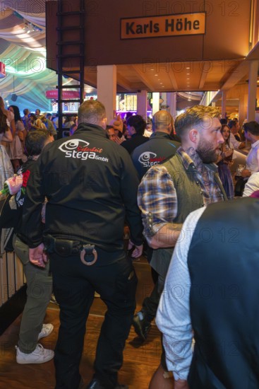 Security guards in a busy marquee during a party, Cannstatter Wasen folk festival, Stuttgart,