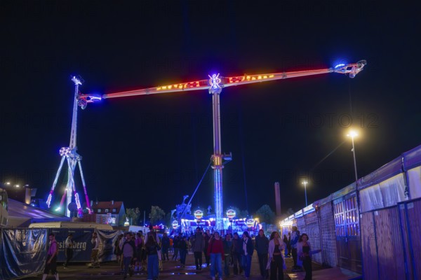 Lively funfair at night with colourful lights and many visitors, Cannstatter Wasen funfair,