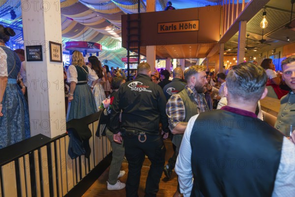 Lively beer tent with security guards and festive atmosphere, Cannstatter Wasen folk festival,