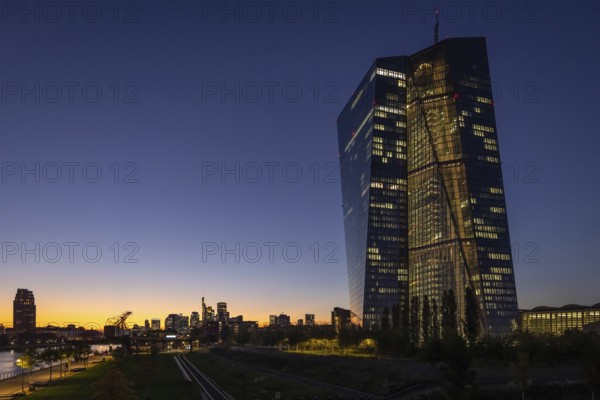 The lights of the European Central Bank (ECB) and the Frankfurt banking skyline glow in the
