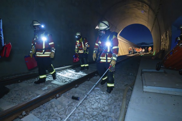 Firefighters walk along tracks in a tunnel at night, firefighting exercise in the new tunnel of the