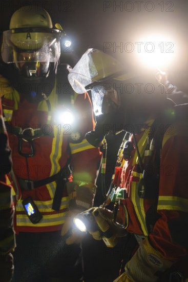 Firefighters in protective suits at night with torches in action, firefighting exercise in the new