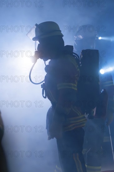 Firefighters with breathing masks in a foggy environment with bright light, firefighting exercise